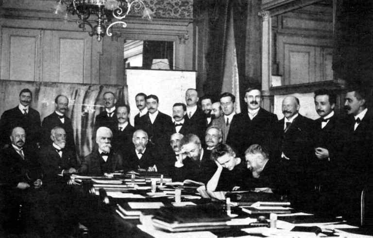 Les participants au congrès Solvay de 1911: Assis (de g. à dr.): Walther Nernst, Marcel Brillouin, Ernest Solvay, Hendrik Lorentz, Emil Warburg, Jean Baptiste Perrin, Wilhelm Wien, Marie Curie et Henri Poincaré. Debout (de g. à dr.): Robert Goldschmidt, Max Planck, Heinrich Rubens, Arnold Sommerfeld, Frederick Lindemann, Maurice de Broglie, Martin Knudsen, Friedrich Hasenöhrl, Georges Hostelet, Édouard Herzen, James Jeans, Ernest Rutherford, Heike Kamerlingh Onnes, Albert Einstein, et Paul Langevin. Hôtel Métropole de Bruxelles. Photo D. R.